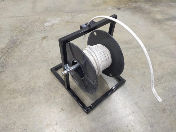 The Solo Sparky. A small compact cable roller/stand viewed from the front left with a drum of cable in installed.